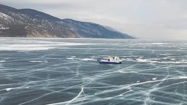 Letecký pohled na typické vznášedlo při cestování po průhledném popraskaném ledovém povrchu. Klip. Jezero Baikal, Sibiř, Rusko, lodní doprava na zamrzlém jezeře. — Stock fotografie