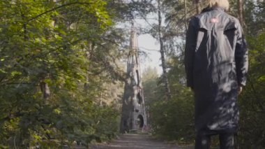 Forest Park 'ta beton kule. Hisse. Adam ormanın ortasındaki beton üçgen kuleye doğru yürüyor. Ormanda üçgen yapısı olan gizemli eski bir yere doğru gidiyor.