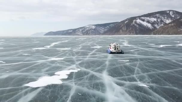 Vue aérienne du véhicule aéroglisseur typique lorsqu'il se déplace sur une surface de glace claire et fissurée. Clip. Lac Baïkal, Sibérie, Russie, transport maritime sur le lac gelé. — Video