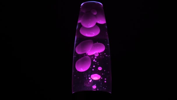 Retro lamp with bubbles. Concept. Beautiful colored bubbles rise and fall in neon lamp on black background. Lava lamp glows brightly in dark — Stock Video