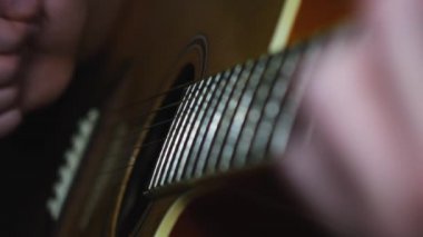 Klasik akustik gitar çalan bir müzisyen. Kavram. Erkek ellerinin gitar çalmasını, karanlık odada akorlar çalmasını, canlı müzik çalmasını..