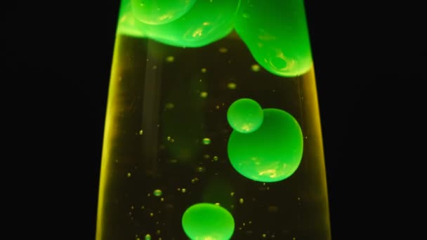 Close-up zicht op groene lava lamp geïsoleerd op zwarte achtergrond. Concept. Ongebruikelijke lamp met schemerig licht en bewegende groene bellen creëren een ontspannen sfeer. — Stockvideo