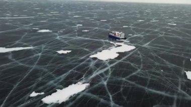 Kış arka planında Khivus makinesinin havası. Şarjör. Baykal Gölü 'nün şeffaf yüzeyinde hızla kayan Hovercraft, doğanın güzelliği..