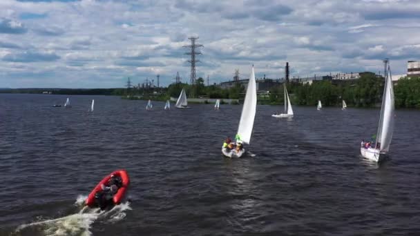 Groep van kleine jachten varen op brede rivier op een zonnige zomerdag. Een video. Mensen van een jachtclub die plezier hebben tijdens het zeilen over het waterreservoir. — Stockvideo