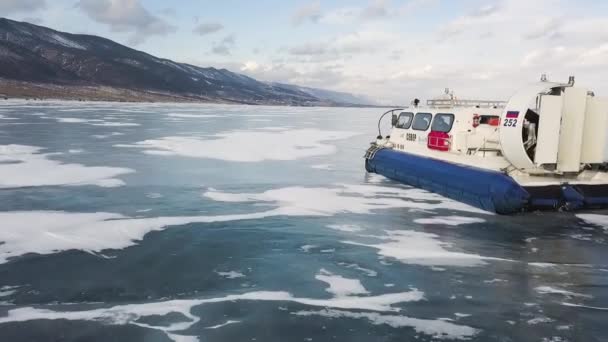 Den hisnande isiga ytan av dammen, bunden av tjock is, och den rörliga svävare. Klipp. Flygfoto av grupp turister som reser inuti luftkudde fordon på den frusna sjön. — Stockvideo