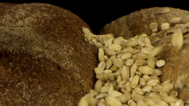 Vers heerlijk brood geïsoleerd op zwarte achtergrond. Voorraadbeelden. Close-up van rustiek roggebrood met krokante korst en vallende zaden, concept van gezonde voeding. — Stockvideo