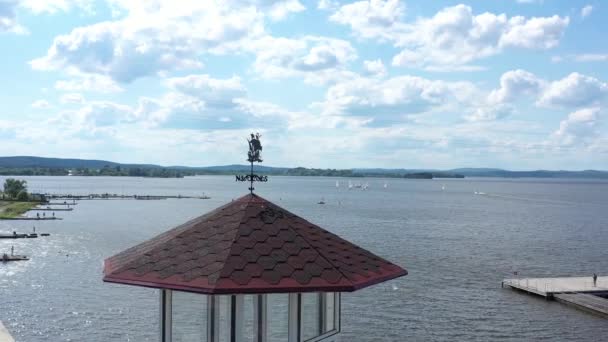 Weather vane in shape of ship. Video. Weather vane ship stands on lighthouse on background of beautiful lake with sailing yachts. Top view of landscape with lake and sailing yachts — Stock Video