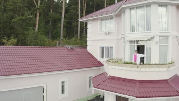 Kvinna som sträcker sig på balkongen. Videon. Ovanifrån av kvinna njuter morgon på balkong av stora landet stuga på bakgrunden av skogen — Stockvideo