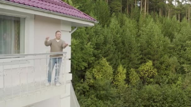 Człowiek uwalnia motyla z rąk. Nagranie. Człowiek stojący na balkonie próbuje uwolnić motyla na wolność na tle lasu. Uwolnienie dużego czarnego motyla z rąk — Wideo stockowe