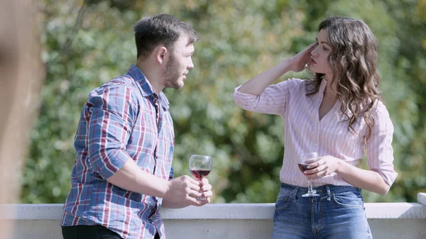 Homem e mulher conversando com copos de vinho na varanda. Vídeo. Homem e mulher conversam em privado na varanda com copos de vinho durante a festa — Fotografia de Stock