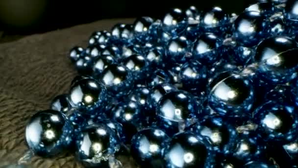 Gros plan de perles bleues guirlande couché sur le tapis. Images d'archives. Fond décoratif avec guirlande de perles brillantes, concept de Noël et Nouvel An vacances d'hiver. — Video