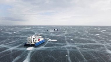 Donmuş muhteşem gölde hareket eden makinenin havadan görüntüsü. Şarjör. Sibirya 'da Baykal Gölü, Rusya' da berrak buz yüzeyindeki tipik bir hovercraft aracı..