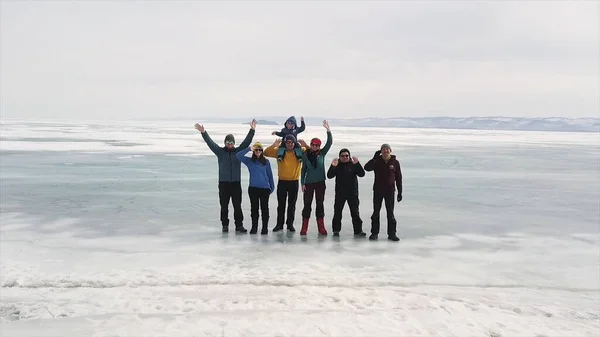 Um grupo de turistas viaja ao longo do gelo do lago congelado Baikal. Clipe. Vista aérea de pessoas felizes acenando para a câmera enquanto estão na superfície gelada, conceito de estilo de vida ativo e extremo — Fotografia de Stock