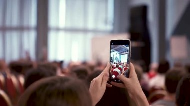 Kadın konferansta telefonda konuşmayı kaydediyor. - Sanat. Profesyonel konferansta kadın film hoparlörleri telefonda konuşuyor. Konferansta halka açık konuşma yapan telefon ekranının yakın çekimi