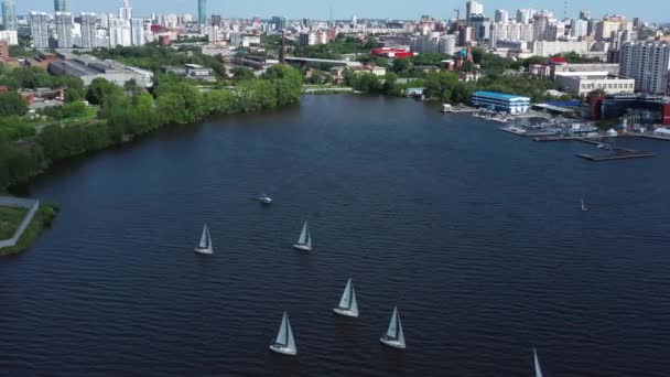 Légi kilátás kikötő fehér gyönyörű vitorlás hajók a városi tóban. Videó. Kis jachtok vitorlázás a móló közelében a háttérben Jekatyerinburg város, Oroszország. — Stock videók
