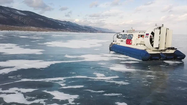 La impresionante superficie helada del embalse, limitada por el hielo grueso, y el aerodeslizador en movimiento. Clip. Vista aérea del grupo de turistas que viajan dentro del vehículo del cojín de aire en el lago congelado . — Foto de Stock