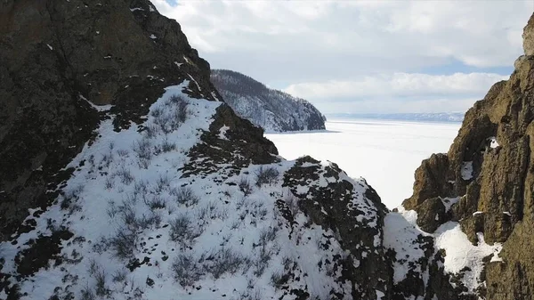 Baikal Lake in winter season, aerial view. Clip. Flying over the rocks and hills near the shore of the frozen amazing water reservoir, the beauty of nature concept. — Stock Photo, Image