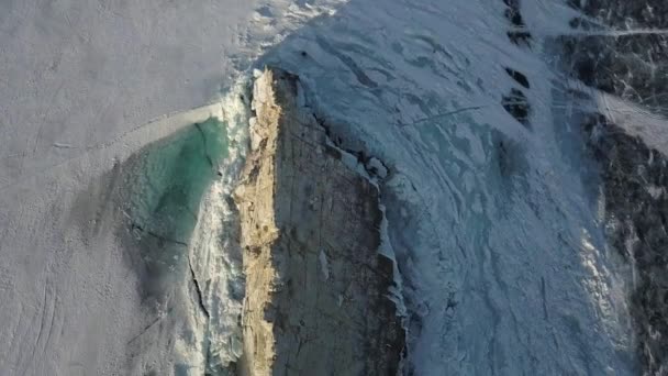 贝加尔湖沿岸的独立石崖，西伯利亚冬季自然。剪断。在冰天雪地的湖底有陡峭的斜坡的岩石的空中景观. — 图库视频影像