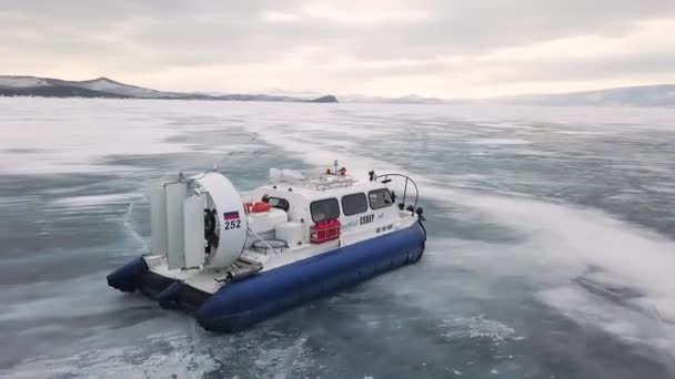 シベリアの湖を渡ってホバークラフト滑り、冬の自然の美しさ。クリップ。氷の上に移動する空気クッション車の空中ビュー、極端な観光の概念. — ストック動画