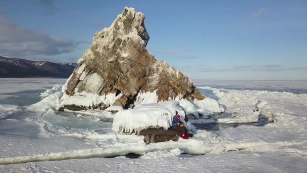 Femme voyageant sur la surface glacée et enneigée du lac. Clip. Vue aérienne d'une femme jouant du tambour de langue en acier assis sur la pierre entourée par le lac gelé Baïkal en hiver, concept de — Video