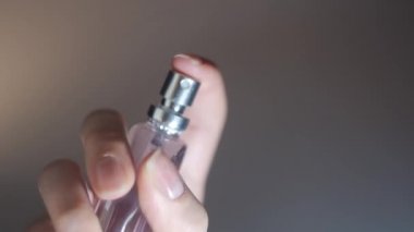 Kadın ellerinin parfüm püskürtmesini kapat. Kavram. Kadının elinde bir bardak, küçük bir şişe parfüm tutarken ve onu havaya savururken en alttaki görüntüsü..