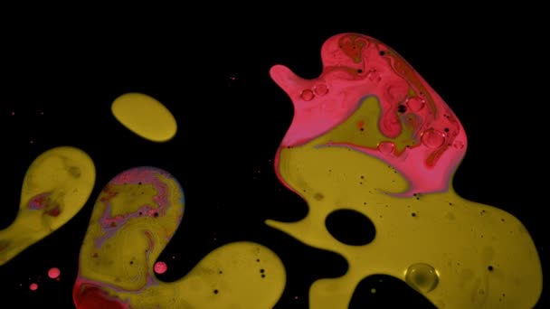 黒の背景に隔離されたスローモーションで液体塗料の質感。ストック映像だ。黒の表面に明るい色の混合と芸術的背景、流体芸術の概念. — ストック動画