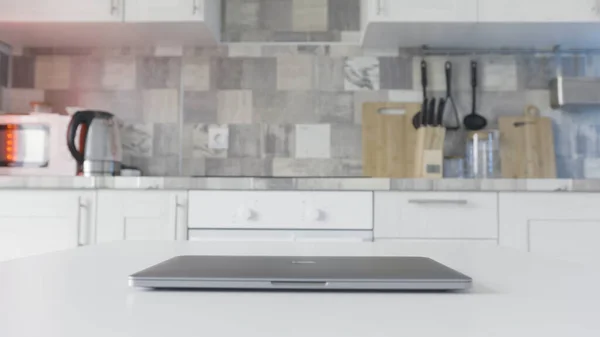 Feche o computador moderno na mesa da cozinha. Acção. Efeito de lapso de tempo, o homem está andando na cozinha em casa e tentando abrir seu laptop cor prata . — Fotografia de Stock