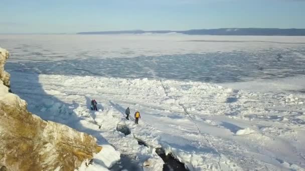 Lago Baikal, belo gelo azul espesso com rachaduras em um dia ensolarado. Clipe. Turistas exploram natureza russa de tirar o fôlego na temporada de inverno, conceito de viagem extrema . — Vídeo de Stock