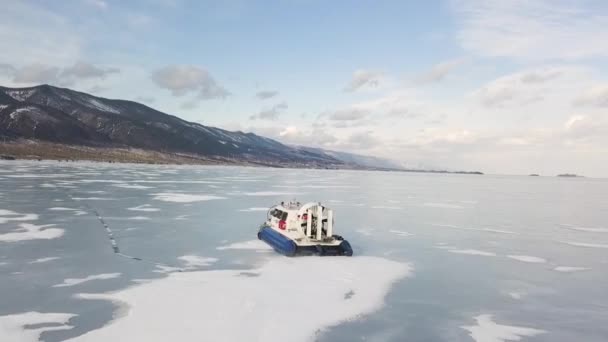 Hovercraft vervoer op het bevroren meer Baikal Siberië, Rusland. Een knip. Luchtfoto van pittoresk winterlandschap met hoge bergen, bevroren meer en blauwe bewolkte lucht. — Stockvideo