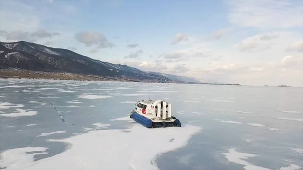 Transporte de aerodeslizadores en el lago congelado Baikal Siberia, Rusia. Clip. Vista aérea del pintoresco paisaje invernal con altas montañas, lago congelado y cielo azul nublado . — Foto de Stock