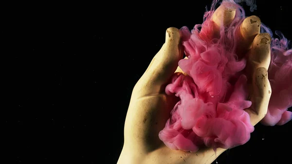 Κοντινό πλάνο του γύψου χέρι τοποθετείται κάτω από το νερό με ροζ σταγόνες μελάνι εξαπλώνεται γύρω. Στικ. Έννοια της τέχνης, το χέρι άγαλμα και πολύχρωμα χρώματα σε μαύρο φόντο. — Φωτογραφία Αρχείου