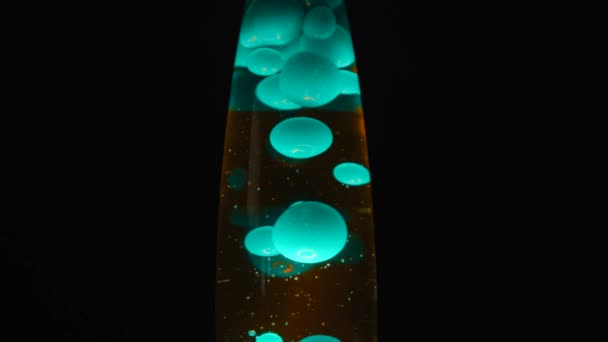 Vista de perto da lâmpada de lava com bolhas móveis azuis. Conceito. Lâmpada de lava de vidro bonita com substância líquida dentro de pé isolada sobre fundo preto . — Vídeo de Stock