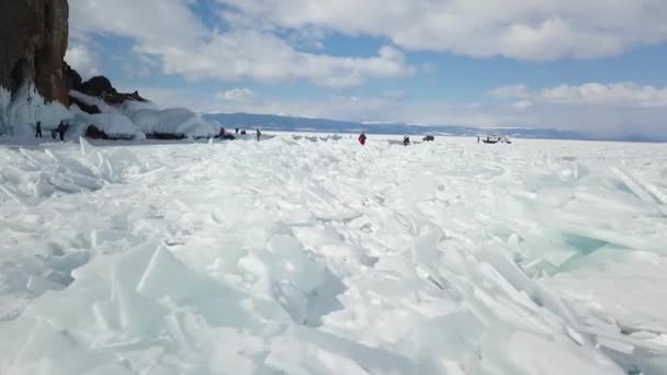 Jezero Bajkal, krásný modrý hustý led s prasklinami za slunečného dne. Klip. Turisté objevovat divoké dech beroucí ruské přírody v zimní sezóně, koncept extrémní cestování. — Stock video