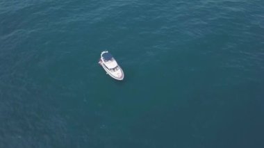 Turkuaz suda yüzen yalnız yatın en üst görüntüsü. Şarjör. Açık mavi okyanusta tek başına yüzen bir yat. Açık denizde yatla deniz gezisi.
