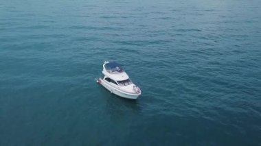 Turkuaz suda yüzen insanların olduğu yatın en üst görüntüsü. Şarjör. Turistler açık denizde tek başlarına yatta rahatlar ve eğlenirler. İnsanlar açık denizde yatın yanında yüzerler.