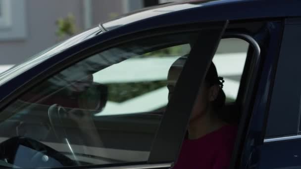 Una donna d'affari caucasica che lascia un'auto. Un video. Donna seria ed elegante che indossa un abito rosa ed esce dalla sua auto di lusso in una giornata di sole. — Video Stock
