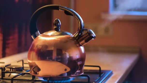 Крупный план серебряного чайника, кипящего на плите. Концепция. Кипящий чайник на плите в красивом вечернем интерьере кухни. Поток пара выходит из чайника на плите — стоковое видео