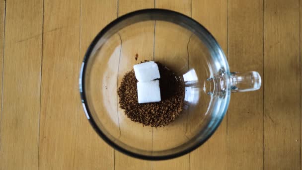 Zbliżenie procesu zaparzania kawy rozpuszczalnej w filiżance. Koncepcja. Góra widok etapów dodawania składników do kawy rozpuszczalnej w przezroczystej filiżance — Wideo stockowe