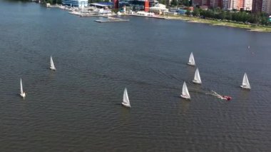 Ekaterinburg 'un arka planında beyaz yelkenli tekneleri olan güzel bir göl manzarası. Video kaydı. Güzel yaz doğa geçmişi, aktif yaşam tarzı ve su sporu kavramı.