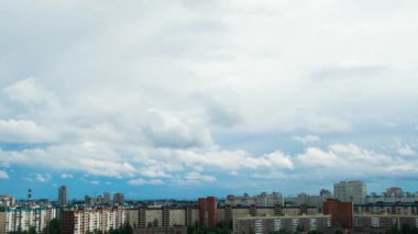 Şehrin panoramik manzarası. Mavi gökyüzü ve yüzen bulutlar. Kavram. Geniş gökyüzü bulutlu büyük şehirlerin evlerinin üzerinde yüzüyor.