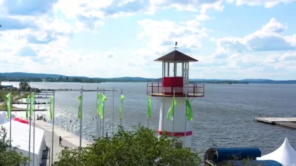 Şehir iskelesindeki Deniz Feneri Gölü. Video kaydı. Yaz setin doğal manzarası, küçük deniz feneri, dağlı yeşil bayraklar ve arka planda mavi bulutlu gökyüzü.. — Stok video