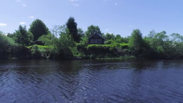 Прекрасний вид з річки на берег з сільським будинком і човном влітку. Постріл. Вид на прекрасний зелений пляж з будинком сільських рибалок у сонячний день — стокове відео