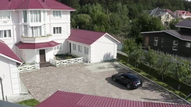 Nuevo aparcamiento azul oscuro caro en frente de la gran casa de campo de tres pisos. Vídeo. Lujo y concepto de prosperidad, el coche se detiene en la hermosa casa de campo con fachada rosa y blanca . — Vídeos de Stock