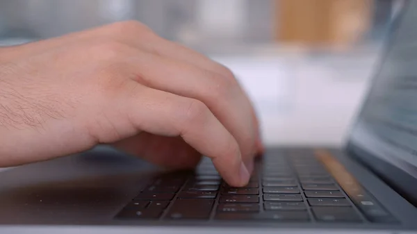 Sidovy av händer trycker på tangenterna i svart laptop knappsats. Börja. Närbild av en keayboard och man händer skriva på modern dator på suddig bakgrund. — Stockfoto