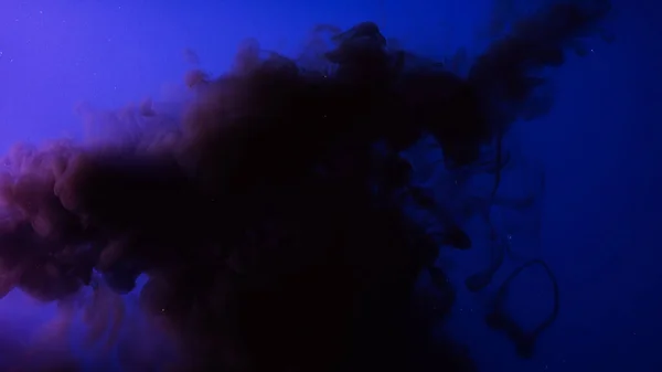 Kolorowe krople farby w wodzie w zwolnionym tempie. Materiał filmowy. Ciemnoniebieski tusz krople farby rozprzestrzenia się w wodzie mieszając się z wodą wyglądającą jak chmura. — Zdjęcie stockowe