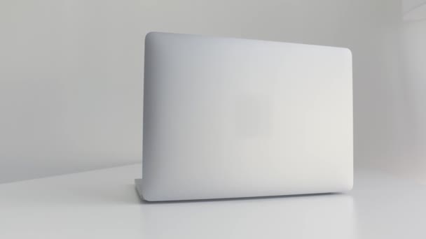 Achteraanzicht van een witte laptop geïsoleerd op witte achtergrond. Actie. Modern slank ontwerp van een nieuwe laptop gemaakt van aluminium materiaal op witte tafel, concept van moderne technologieën. — Stockvideo