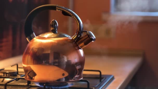 Una tetera de metal plateado en una estufa de gas en la cocina en casa. Concepto. Cierre de la tetera de acero con agua hirviendo, preparación de bebidas calientes . — Vídeo de stock