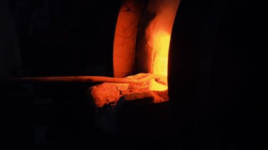 Ocaktaki kömürleri siyah arka planda bir demiriyle boğmaya çalış. Stok görüntüleri. Geleneksel Rus fırınının içinde yanan alevin yan görüntüsü.