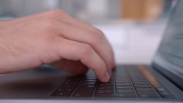 Vista lateral das mãos pressionando as teclas do teclado do laptop preto. Acção. Close-up de um keayboard e mãos de homem digitando no computador moderno em fundo embaçado . — Vídeo de Stock