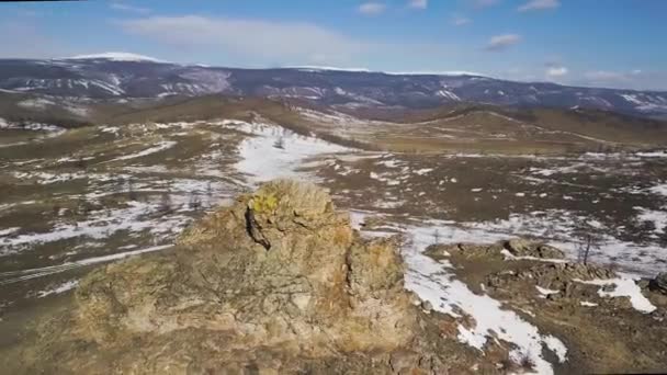 Letecký pohled na přírodní krajinu se zasněženými kopci. Klip. Venkovské pozadí se žlutou loukou, lesem a horami na konci podzimu. — Stock video